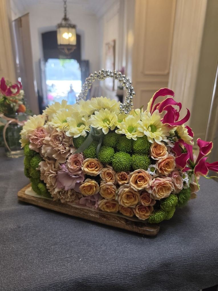 Bolso floral con asa de perlas hecho con rosas beige, crisantemos verdes y gloriosa fucsia, pieza especial del atelier