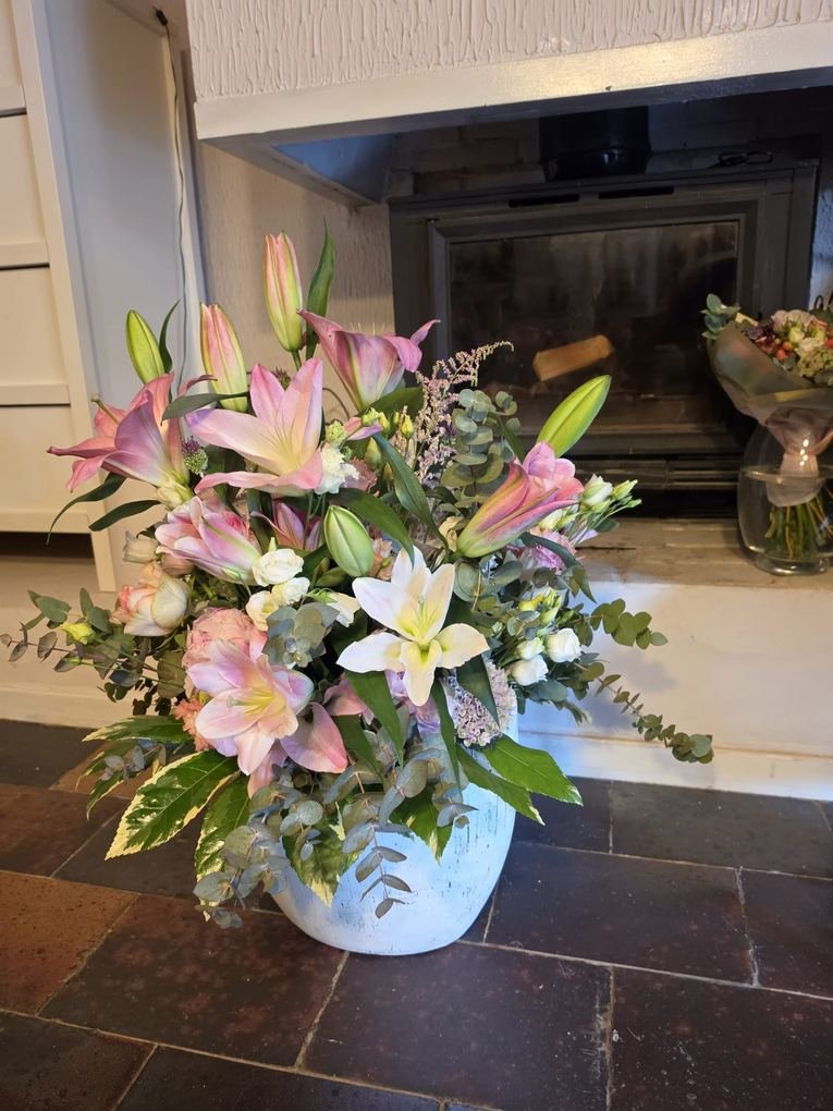 Centro de lirios rosados y blancos con eucalipto en maceta de cerámica, para decorar el interior de casa