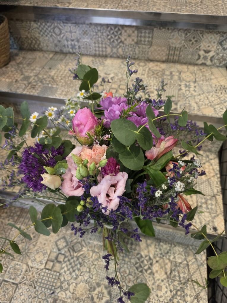 Ramo campestre en tonos malva y rosa con eucalipto y limonium, sobre el suelo hidráulico de la tienda